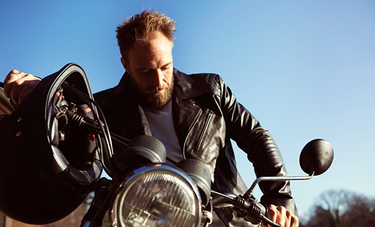 Muž s motorkou v kořené bundě na zip